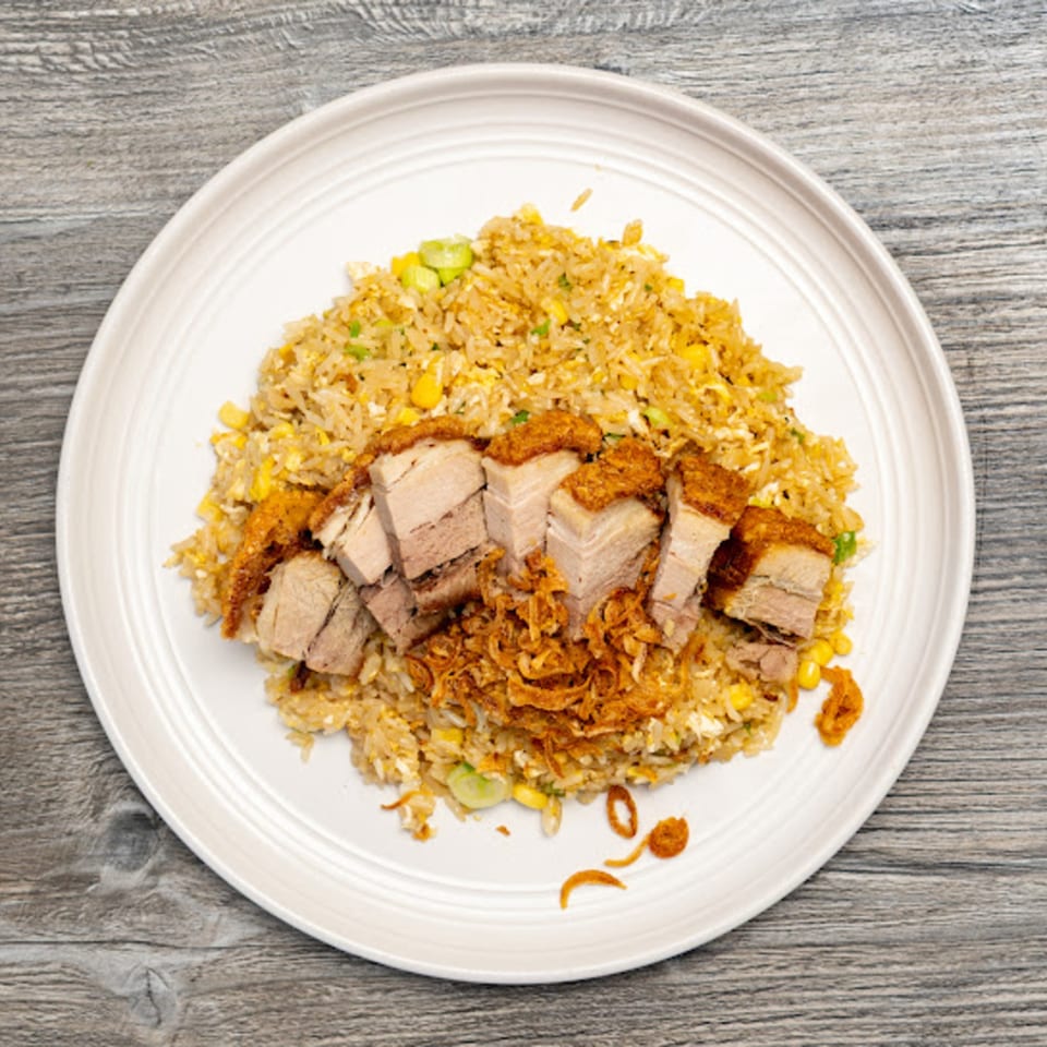 Motto Ramen's fried rice with crispy pork belly and fried onions on a white plate.