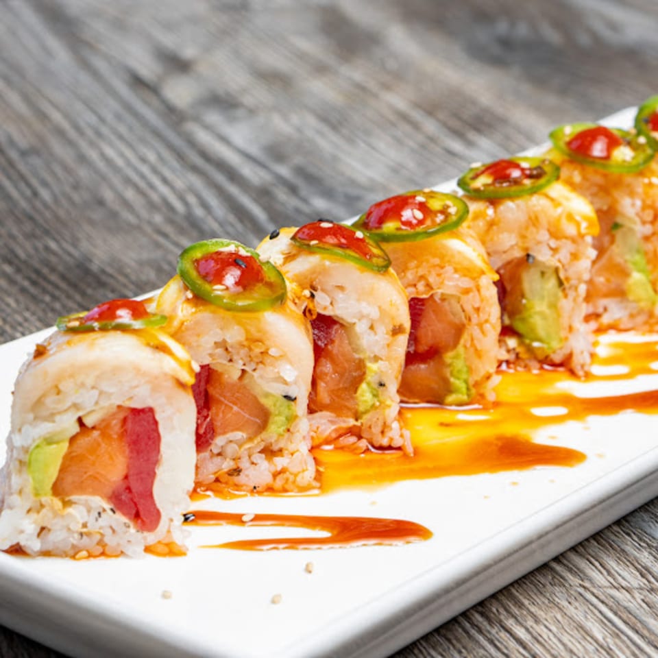 Spicy sushi rolls with tuna, avocado, jalapeno, and red sauce on a white plate.