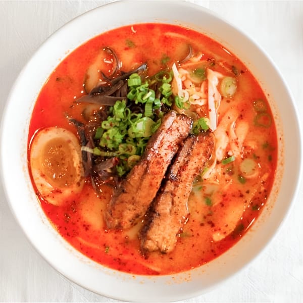 Motto Ramen's spicy ramen bowl with pork belly, soft-boiled egg, and green onions.