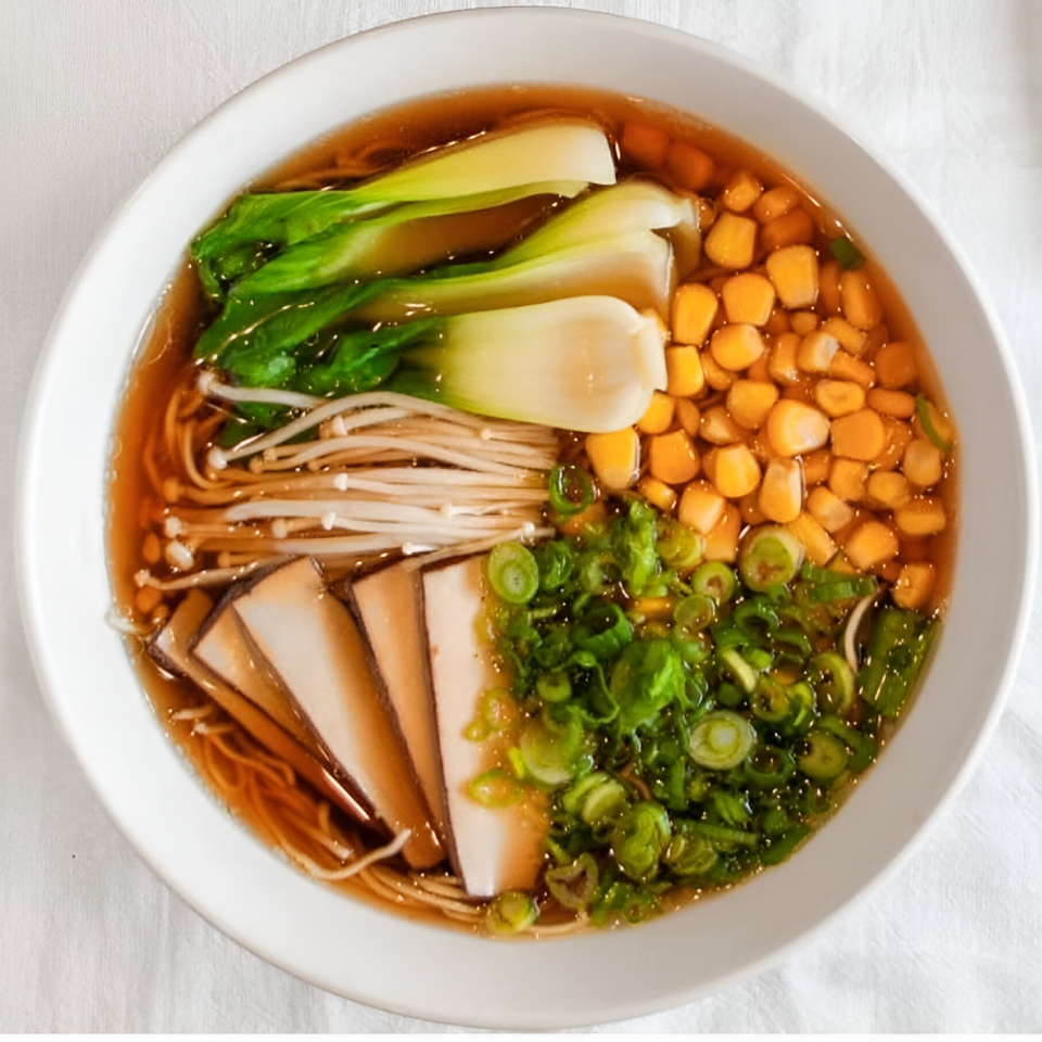Overhead view of Motto Ramen's ramen bowl with bok choy, corn, mushrooms, and scallions.